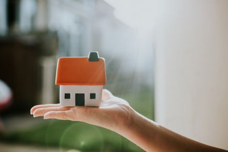 Person holding ceramic house figurine